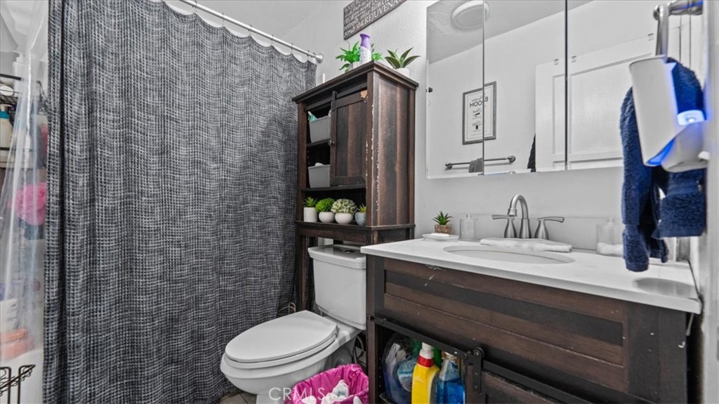 1030 North Western Avenue Colton, CA 92324 - Photo 19 of 32 a bathroom with a sink a toilet a mirror and shower curtain
