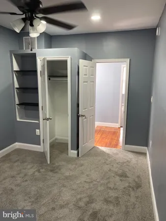 an empty room with closet and a ceiling fan