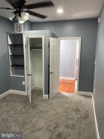 an empty room with closet and a ceiling fan