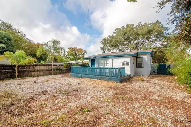 a view of a house with wooden fence next to a yard