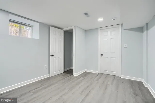 a view of an empty room with wooden floor and closet