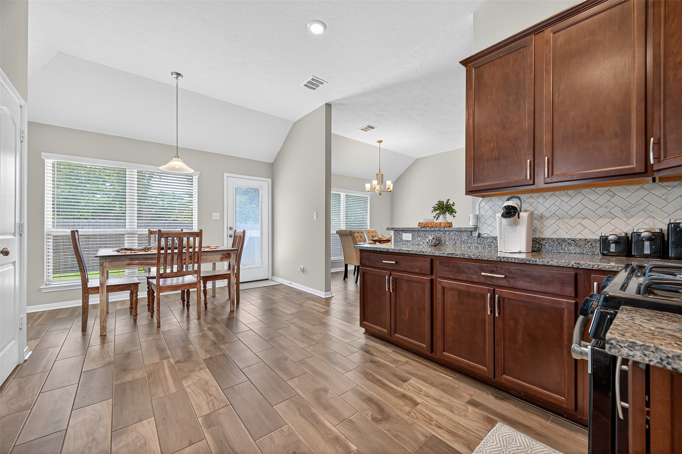 128 Red Deer Way Huntsville, TX 77320 - Photo 16 of 33 a kitchen with stainless steel appliances granite countertop wooden cabinets a dining table and chairs