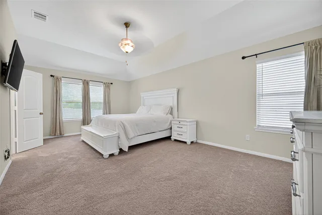 a spacious bedroom with a bed and a flat tv screen