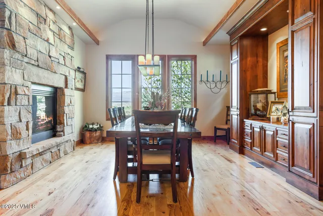 a dining room with wooden floor a chandelier a wooden table and chairs