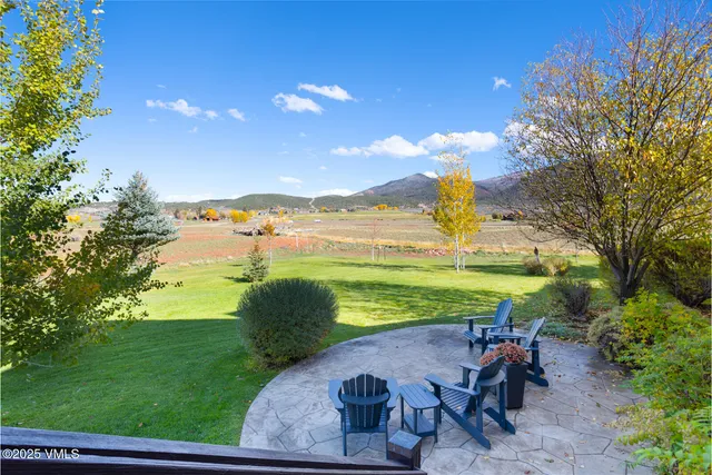 a kitchen with granite countertop a stove a sink dishwasher a dining table and chairs with wooden floor