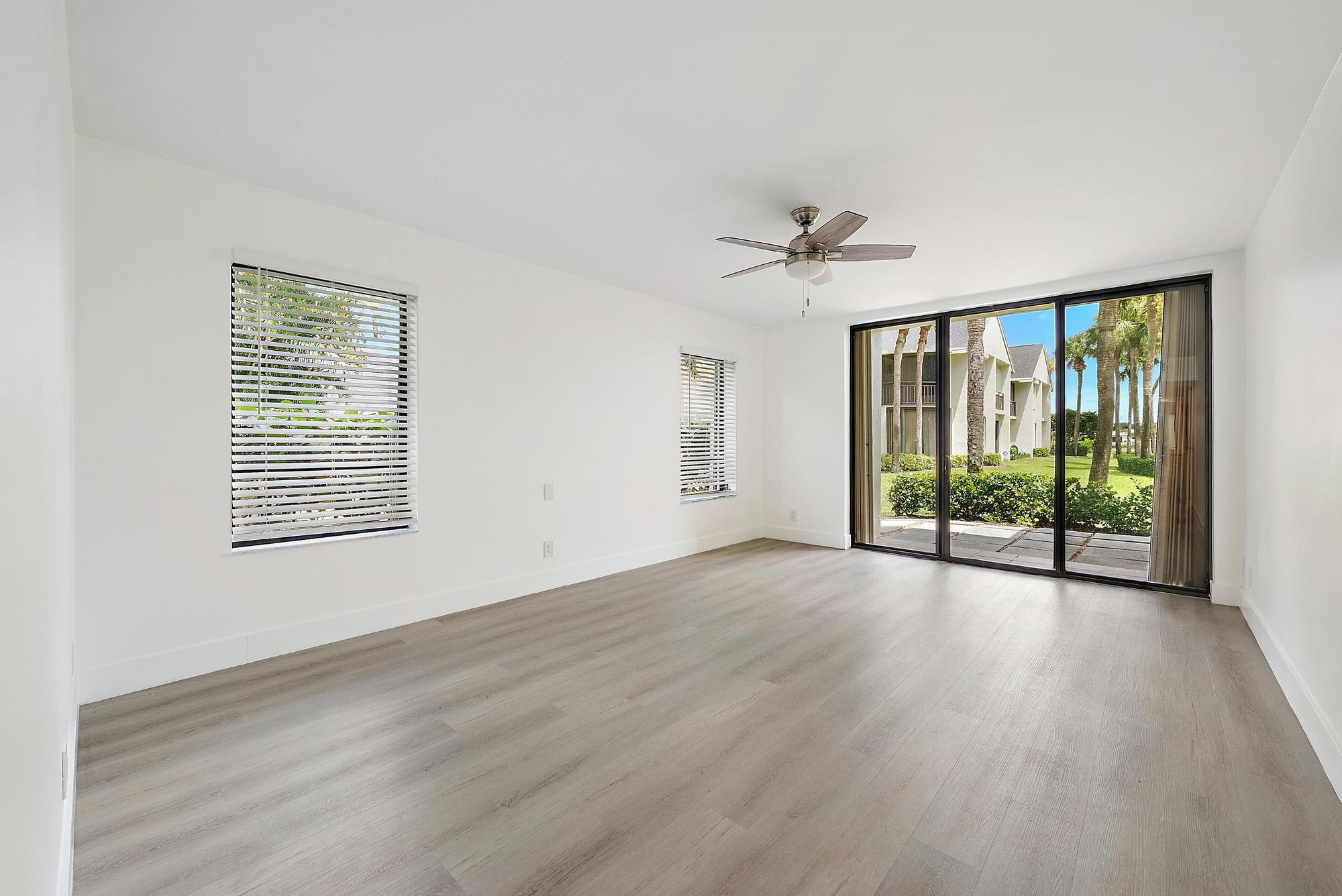 10459 Southeast Terrapin Place, Unit 101D Jupiter, FL 33469 - Photo 17 of 49 a view of an empty room with a window and wooden floor