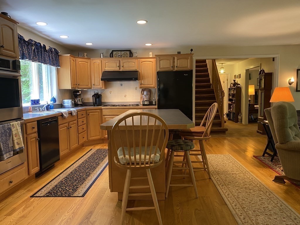 76 Main Road Gill, MA 01354 - Photo 7 of 36 a kitchen with stainless steel appliances granite countertop a refrigerator a stove top oven and a dining table with wooden floor