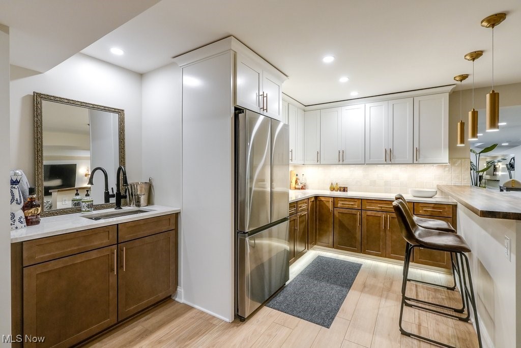 1598 Graham Road Silver Lake, OH 44224 - Photo 40 of 46 Kitchen with hanging light fixtures, light wood-type flooring, white cabinetry, sink, and stainless steel fridge