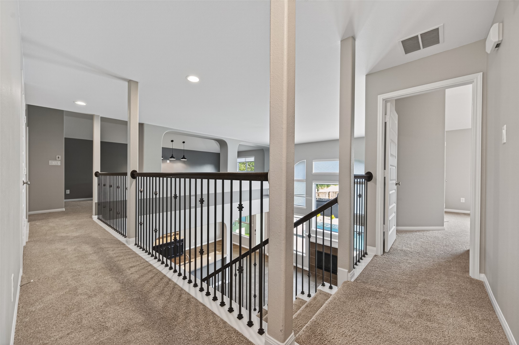 7003 Bristol Memorial Drive Spring, TX 77379 - Photo 25 of 40 Expansive second-floor landing in this Spring TX 77379 home featuring iron balusters and open-to-below views overlooking the two-story living area. One side of the upper level offers a spacious game room with elevated sightlines, plus a separate flex room that can function as a sixth bedroom, media room, or private office and includes access to a balcony. The opposite wing features four private secondary bedrooms and two full bathrooms, creating a well-designed layout with separation and functionality.