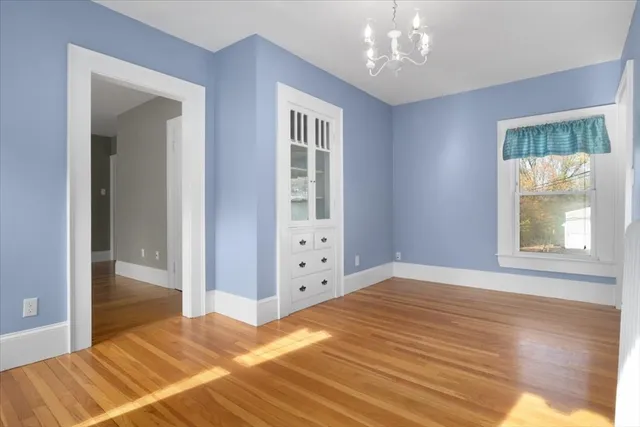 a view of an empty room with window and wooden floor