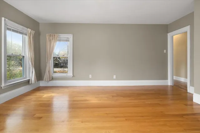 a view of an empty room with window and wooden floor
