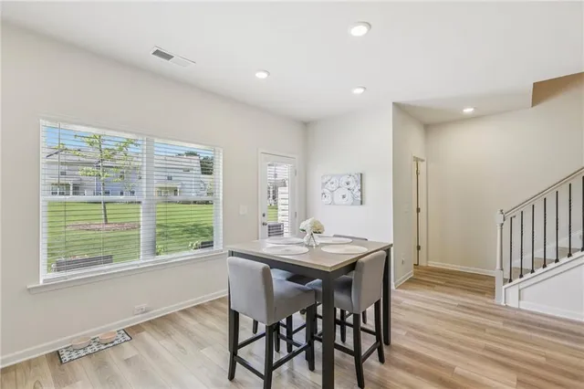 a kitchen with stainless steel appliances granite countertop a stove top oven a sink dishwasher a dining table and chairs with wooden floor