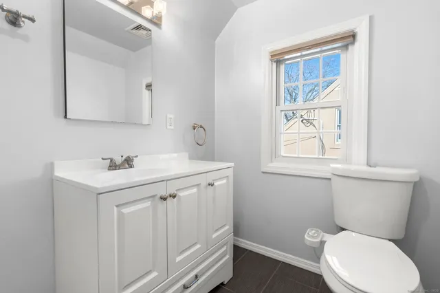 a bathroom with a toilet a sink a vanity and mirror