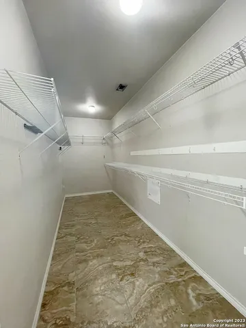 an empty room with wooden floor chandelier and windows