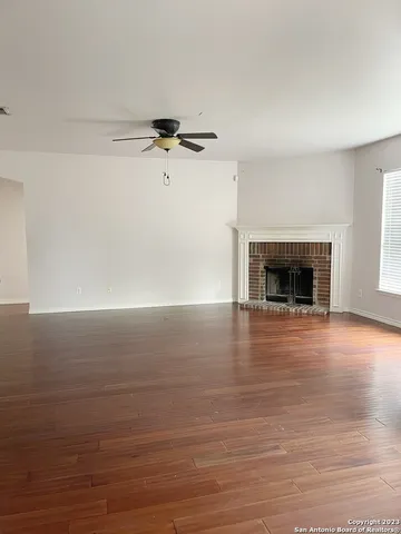 an empty room with wooden floor fireplace and windows
