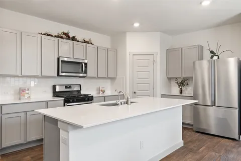 a kitchen with kitchen island a sink appliances and cabinets