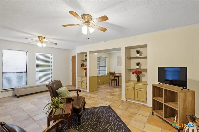 a living room with furniture a flat screen tv and kitchen view