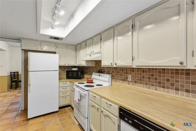 a kitchen with a refrigerator a stove a sink and cabinets