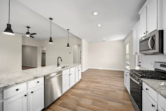 a large kitchen with stainless steel appliances kitchen island granite countertop a sink and cabinets