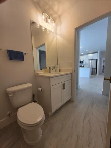 a bathroom with a toilet a sink a mirror and vanity