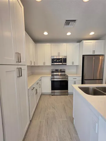 a kitchen with kitchen island stainless steel appliances a refrigerator sink and microwave
