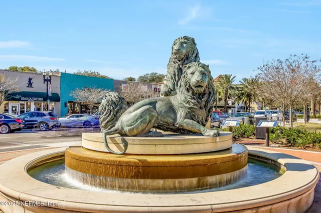 a front view of a building with garden and trees