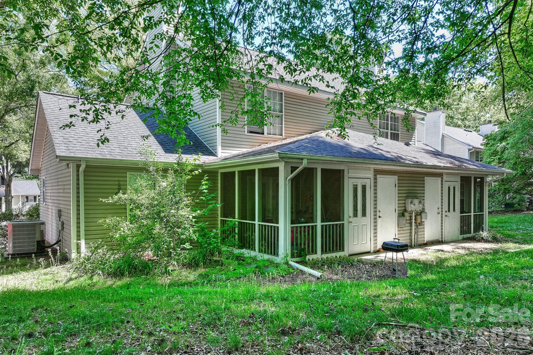 6725 Bevington Ridge Road, Unit A/B Charlotte, NC 28277 - Photo 24 of 48 a view of a house with a large window and a yard with plants and a large tree
