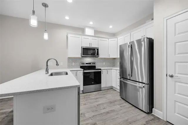 a kitchen with kitchen island a sink stainless steel appliances and refrigerator