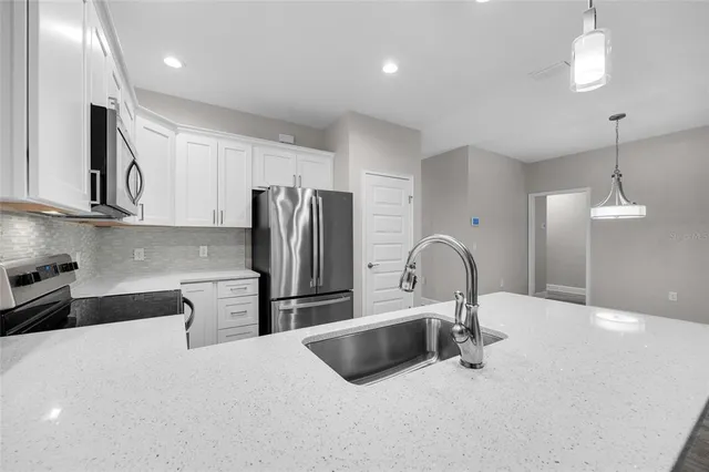 a kitchen with stainless steel appliances a sink a stove a refrigerator and cabinets