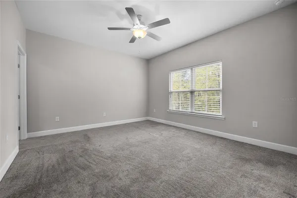 an empty room with windows and ceiling fan