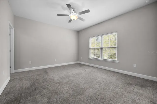 an empty room with windows and ceiling fan