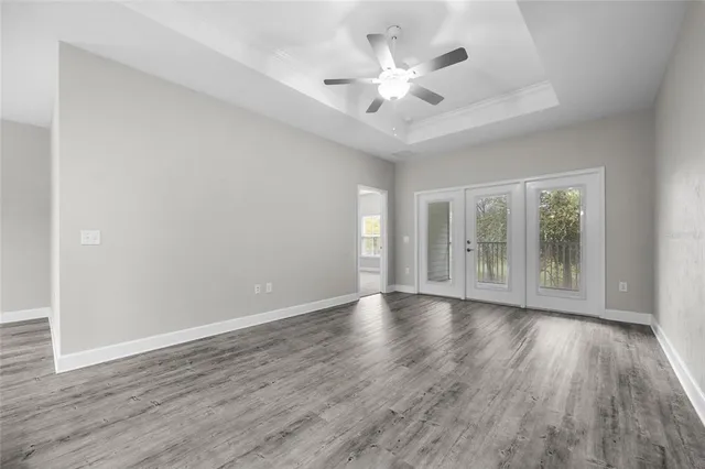 a view of an empty room with a window and wooden floor