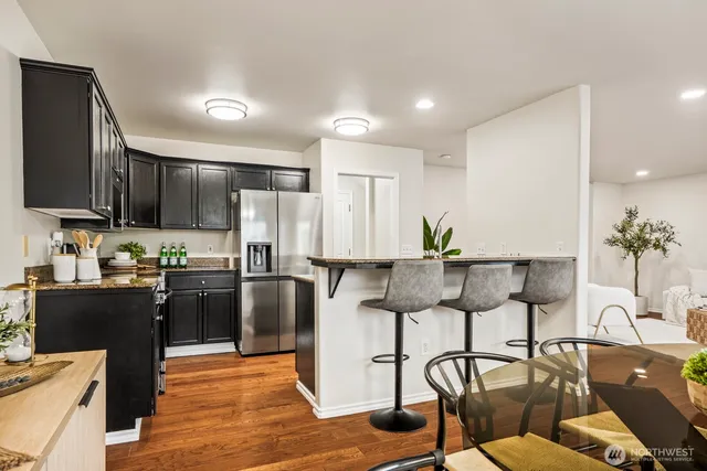 a kitchen with stainless steel appliances granite countertop a refrigerator a stove a sink dishwasher and white cabinets with wooden floor