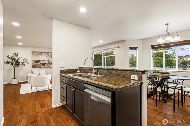 a kitchen with stainless steel appliances granite countertop a stove top oven a dining table and chairs with wooden floor