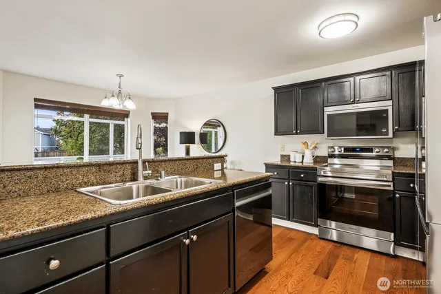 a kitchen with stainless steel appliances granite countertop a sink stove and microwave