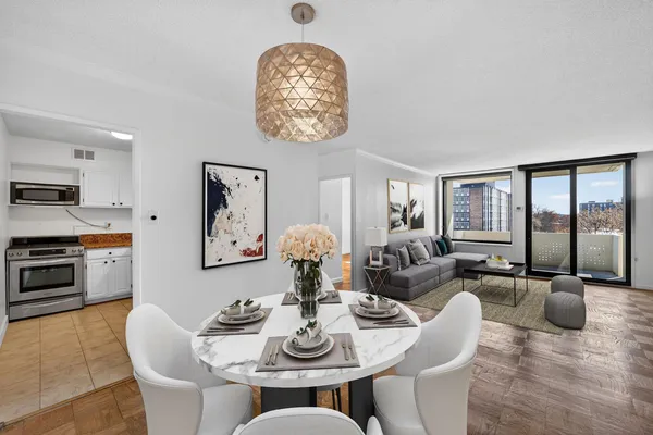 a dining room with furniture a chandelier a large window and wooden floor