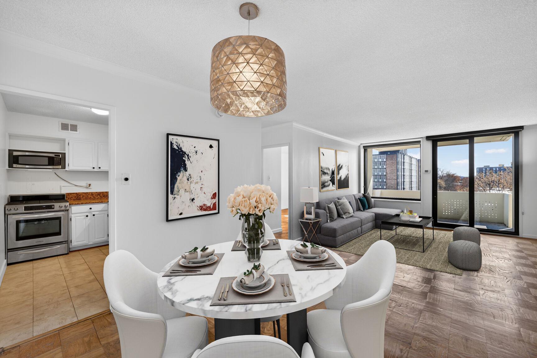 a dining room with furniture a chandelier a large window and wooden floor