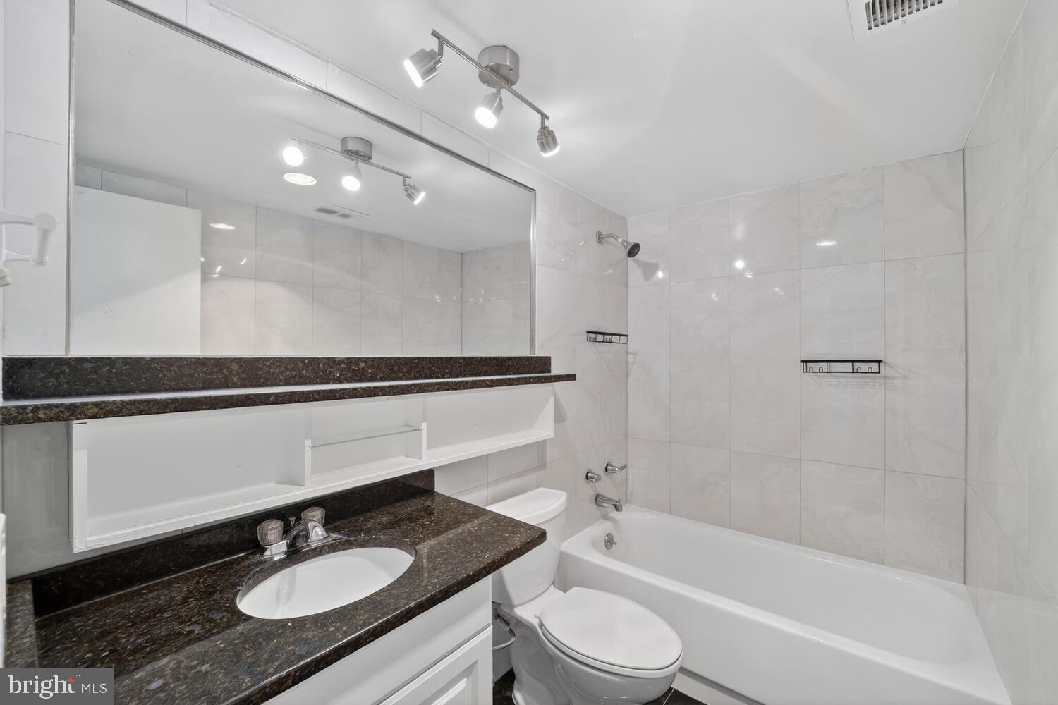 240 M Street Southwest, Unit E406 Washington, DC 20024 - Photo 14 of 38 a bathroom with a granite countertop sink a toilet a mirror and shower