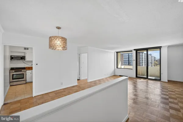 a view of an empty room with window and wooden floor