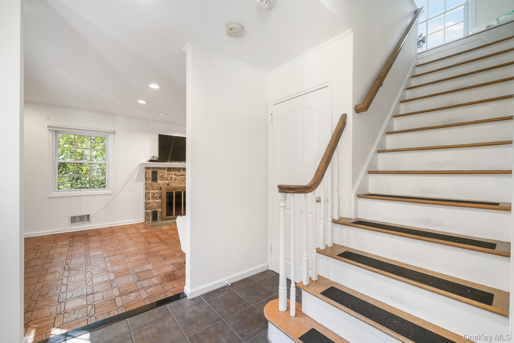 29 Chatfield Road Bronxville, NY 10708 - Photo 4 of 27 Stairs with recessed lighting, a stone fireplace, and tile patterned flooring
