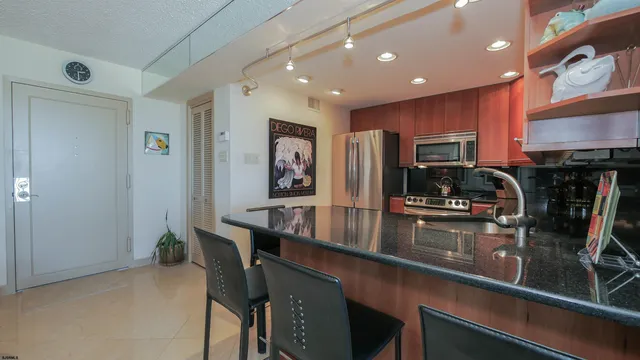 a kitchen with stainless steel appliances a sink a stove a refrigerator cabinets and a dining table