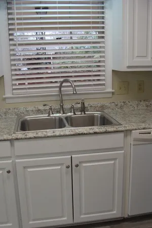 a kitchen with granite countertop white cabinets and a sink