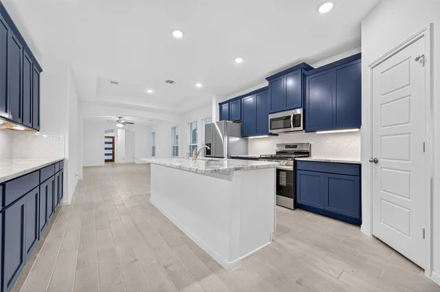 a open kitchen with kitchen island granite countertop a large counter top and stainless steel appliances