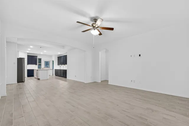 a view of empty room with wooden floor and ceiling fan