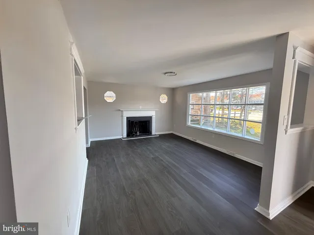 an empty room with wooden floor fireplace and windows