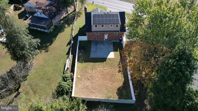 a backyard of house with wooden fence and a large tree