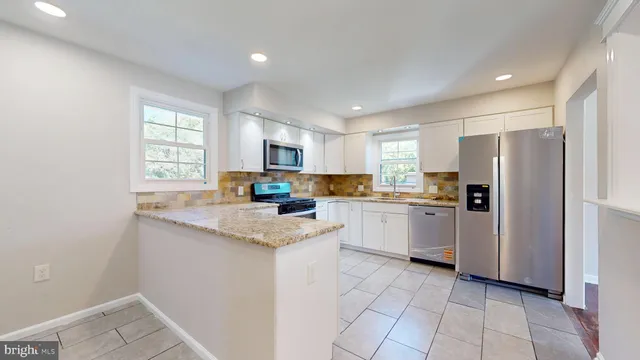 a kitchen with a refrigerator a sink dishwasher a stove and white cabinets with wooden floor