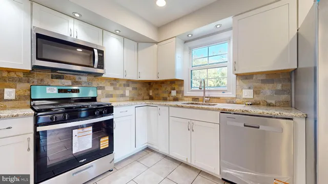a kitchen with granite countertop a stove top oven sink and cabinets