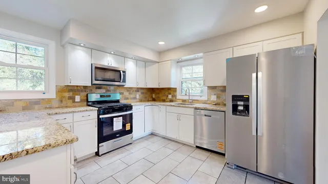 a kitchen with granite countertop cabinets stainless steel appliances and a window