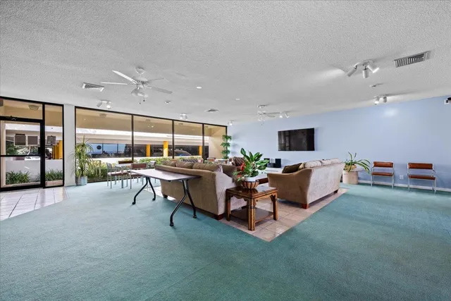 a living room with furniture a floor to ceiling window and flat screen tv